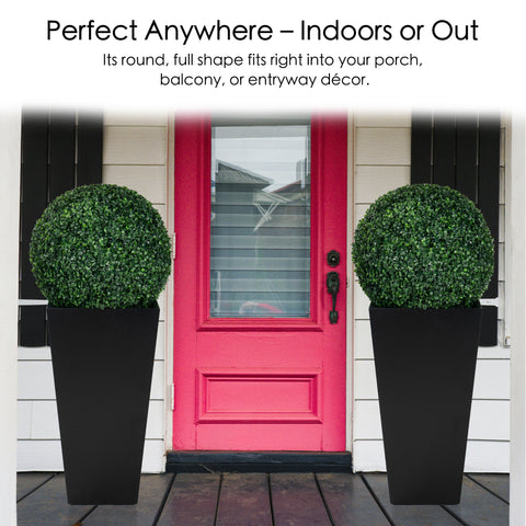 Two artificial topiary balls in black planters, placed symmetrically on either side of a vibrant red front door. Their round, full shape is perfect for enhancing indoor or outdoor decor, such as porches, balconies, or entryways. Artificial Topiary Balls for Indoor and Outdoor Decor. Artificial topiary balls, faux green plant spheres, indoor - outdoor decor