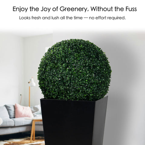An artificial topiary ball in a black planter, placed indoors in a modern living room setting. The lush, green sphere offers the look of fresh greenery with no maintenance required, enhancing the decor effortlessly. Artificial Topiary Ball - Effortless Greenery Indoors. Artificial topiary ball, faux green plant sphere, low - maintenance greenery.