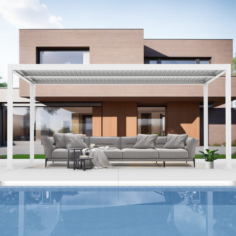 A sleek white louvered pergola provides shade over a modern outdoor lounge area. The setup features a large grey sofa with matching cushions, small side tables, and a potted plant, set against the backdrop of a contemporary brick house and a pool. White Louvered Pergola for Modern Outdoor Living. louvered pergola, modern outdoor lounge, white pergola, contemporary house, poolside.