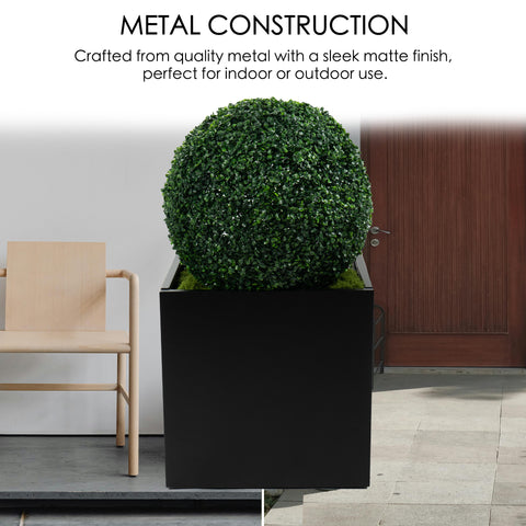 A black cube - shaped metal planter with a sleek matte finish, crafted from quality steel. It holds a lush, spherical green plant, suitable for both indoor and outdoor use, enhancing any space with its modern design. Black Cube Metal Planter - Quality Steel Construction. cube metal planter, steel planter box, black steel flower pot, metal construction.