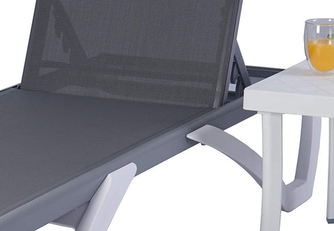 A close - up view of a modern outdoor lounge bed with a gray breathable Textilene fabric. The lounge bed has a sleek, contemporary frame in light grey and white, and is positioned next to a white side table with a glass of orange juice on it. Contemporary Outdoor Lounge Bed with Breathable Fabric. outdoor lounge bed, breathable Textilene fabric, modern design, side table.