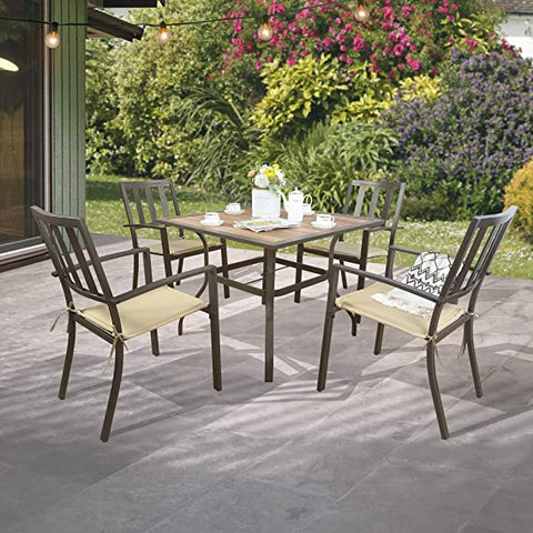 A set of outdoor dining chairs with a dark brown metal frame and beige cushions is arranged around a square table on a patio. The scene is set in a garden with greenery and colorful flowers in the background, and string lights are hanging above, creating a cozy outdoor dining atmosphere. Outdoor Dining Chairs: Stylish Seating for Patio Meals. outdoor dining chairs, metal frame chairs, beige cushioned chairs, patio furniture, garden dining