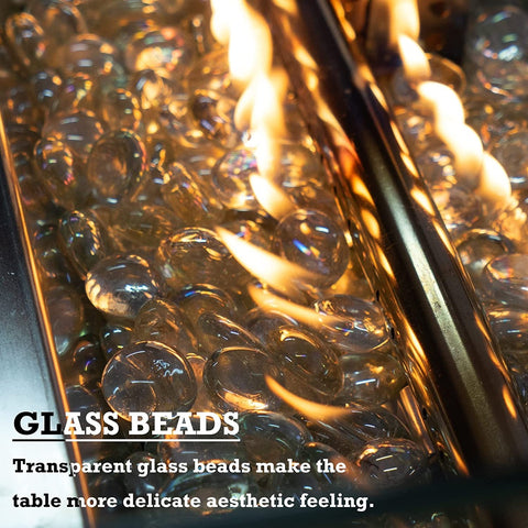 A close - up view of a fire pit table filled with transparent glass beads, through which flames are flickering. The text "GLASS BEADS" and "Transparent glass beads make the table more delicate aesthetic feeling" emphasizes the aesthetic appeal of the glass beads in the fire pit.Fire Pit Table with Aesthetic Glass Beads.fire pit table, glass beads, transparent fire pit decor, aesthetic patio furniture, outdoor fire feature