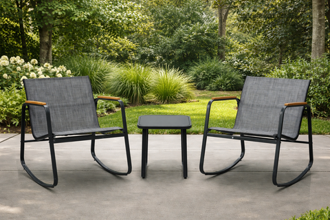 Kozyard outdoor rocking chair set with two sling chairs and a matching side table on a patio, styled with a lush garden and greenery backdrop