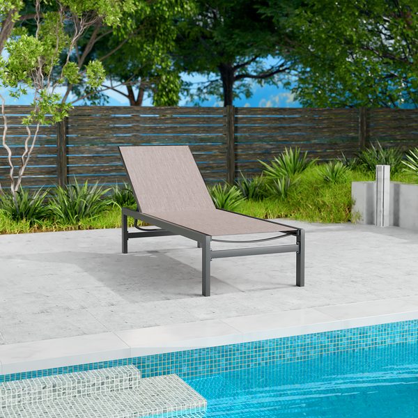 A beige outdoor lounge chair with a sleek black metal frame is positioned beside a swimming pool. The setting includes a wooden fence, green plants, and a concrete patio, creating a serene and relaxing outdoor environment. Beige Outdoor Lounge Chair: Relax by the Poolside. beige lounge chair, outdoor lounge chair, poolside furniture, black metal frame, relaxation.