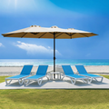 A beige Outdoor Patio Double - Sided Aluminum Umbrella stands on a patio area near a beach. Under the umbrella, there are three blue and white lounge chairs arranged, providing a comfortable spot for relaxation. The backdrop features a clear blue sky, the ocean, and sandy beach, highlighting the umbrella's suitability for outdoor leisure settings.Beige Outdoor Patio Double - Sided Aluminum Umbrella: Beachside Relaxation. beige outdoor umbrella, double - sided aluminum umbrella, patio umbrella, beach lounge.