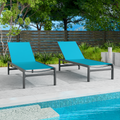 Two blue outdoor lounge chairs with dark frames are positioned beside a swimming pool. The background includes greenery and a wooden fence, creating a relaxing outdoor setting. blue outdoor lounge chairs, poolside furniture, outdoor relaxation, dark-framed lounge chairs.

