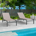 Two beige outdoor lounge chairs with dark frames are positioned beside a swimming pool. The background includes greenery and a wooden fence, creating a relaxing outdoor setting. Beige Outdoor Lounge Chairs: Relax by the Poolside.beige outdoor lounge chairs, poolside furniture, outdoor relaxation, dark - framed lounge chairs