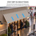 Kozyard 135 inch metal awning featuring an integrated front gutter system that channels rainwater toward the canopy edges during heavy rainfall. Installed above a commercial storefront entrance, this wall mounted outdoor rain canopy helps protect customers and entryways from direct rain exposure. Ideal for restaurant entrance awnings, commercial door canopies, exterior window covers, and residential rain shelters requiring extended overhead protection.