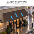 Kozyard 149 inch metal awning featuring an integrated front gutter designed to channel rainwater toward the canopy edges during heavy rainfall. Installed above a commercial storefront entrance, this wide wall mounted rain canopy helps reduce direct rain exposure for customers waiting or entering the building. Ideal for retail shop awnings, restaurant entrances, cafe storefronts, commercial door canopies, business entryways, wide patio doors, and outdoor rain protection applications.