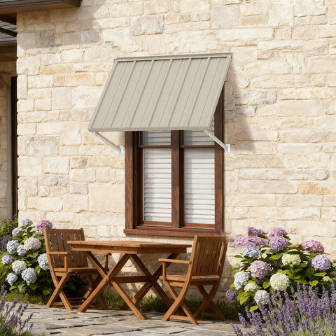 Kozyard 42-inch aluminum window awning and door canopy in beige metal panels with adjustable support arms, installed on a rustic stone wall over a double-hung window next to patio furniture and flowers. Perfect heavy-duty outdoor sun shade and rain protection for residential home improvement.