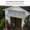 Kozyard exterior door awning highlighting the functional stay dry in heavy rain gutter drainage system channel. The educational graphic shows blue arrows indicating efficient rainwater diversion, routing downpours away from the main front entrance to keep the porch patio walkway completely dry. Perfect for storms, winter blizzards, and rainy seasons, this protective corrugated metal canopy cover shields homeowners, gardeners, and door hardware from water damage and moisture leaks.