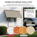Kozyard metal awning wall compatibility diagram showcasing easy installation on multiple siding surfaces like brick walls, concrete walls, and wood walls. The outdoor application picture features the dark gray canopy mounted securely next to a driveway parking space with a Tesla Cybertruck. The complete kit package includes high-quality stainless steel screws and heavy-duty wall anchors, guaranteeing a straightforward DIY installation process over utility meters or side garage doors.