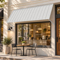 Kozyard 95 inch metal awning installed above a commercial coffee shop window, featuring a wide corrugated metal roof panel and adjustable support arms mounted to an exterior brick wall. This 7.92 FT outdoor window canopy provides overhead shade and rain protection for storefront windows and outdoor customer seating areas. Ideal for cafe storefront awnings, restaurant windows, commercial building facades, retail shop entrances, sidewalk seating areas, and residential exterior window covers.