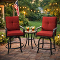 Kozyard swivel bar stools with cushions arranged around a matching small round bistro table with drinks on a paved stone patio backyard setup illuminated by warm outdoor string lights.