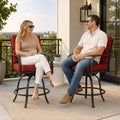Kozyard modern outdoor swivel bar stools with armrests being enjoyed by a man and woman drinking wine and relaxing on a stylish apartment balcony overlooking urban residential buildings.