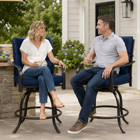 Kozyard modern outdoor swivel bar stools with armrests being enjoyed by a man and woman drinking wine and relaxing on a stylish apartment balcony overlooking urban residential buildings.