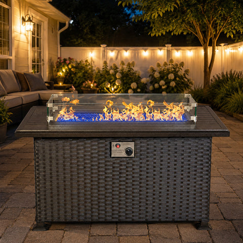Kozyard propane fire pit table creates a warm and inviting outdoor patio centerpiece with a modern gray wicker base, durable aluminum tabletop, clear glass wind guard, blue fire glass and adjustable gas flame. This rectangular outdoor gas fire table is ideal for backyard, deck, garden and patio seating areas, combining stylish outdoor furniture with a clean-burning propane fire pit for entertaining, relaxing and cozy evenings.