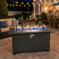 Kozyard propane fire pit table creates a warm and inviting outdoor patio centerpiece with a modern gray wicker base, durable aluminum tabletop, clear glass wind guard, blue fire glass and adjustable gas flame. This rectangular outdoor gas fire table is ideal for backyard, deck, garden and patio seating areas, combining stylish outdoor furniture with a clean-burning propane fire pit for entertaining, relaxing and cozy evenings.