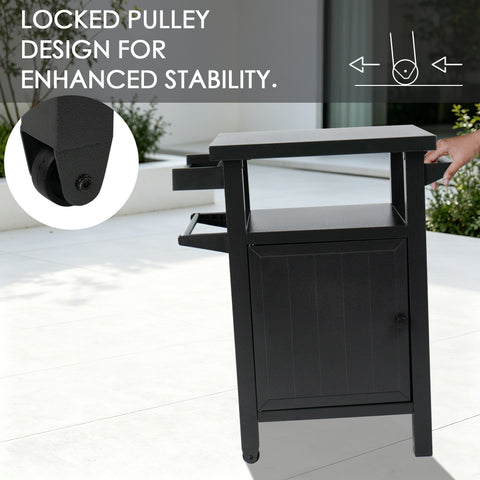 Kozyard movable outdoor prep table highlighting the locked pulley design for enhanced stability and safety. The diagram illustrates how the heavy-duty caster wheel locks securely to prevent the grilling cart from sliding during food preparation or BBQ cooking. A person's hand holds the side handle, demonstrating the smooth mobility and reliable stationary control of this gray metal patio utility cart.