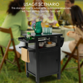 A black BBQ grill storage cart/bin is featured in an outdoor setting with people dining in the background. The cart holds various items like a green pitcher, glasses, a bottle, a mixing bowl, and plates. A napkin hangs from one of its sides. The text at the top reads "USAGE SCENARIO This storage cart is suitable for outdoor barbecues, kitchen islands, parties, bars, etc."Versatile BBQ Grill Storage Cart for Multiple Occasions. BBQ grill storage cart, storage bin, outdoor barbecues, kitchen islands, parties