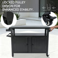 Kozyard movable large outdoor prep table demonstrating the locked pulley design for maximum stability during food preparation. The technical graphic highlights both the standard caster wheel and the premium step-lock brake wheel. A hand holds the side handle bar, showing how easily this 60 lbs powder-coated metal BBQ grill cart transitions from a mobile serving cart to a rock-solid stationary prep station.