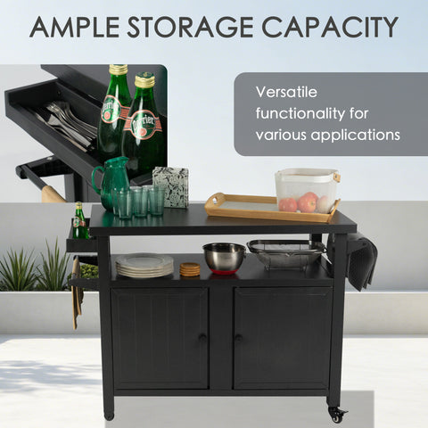 Kozyard ample storage capacity outdoor kitchen island highlighting versatile functionality. The open setup showcases stacked dinner plates, bowls, a beverage pitcher, glass cups, a wooden serving tray, and an apple basket on the tabletop and open middle shelf. A slide-out spice tray keeps utensils and refreshments organized, making this heavy-duty rolling bar cart perfect for hosting large garden parties.