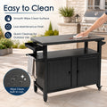 Kozyard easy-to-clean large outdoor grill cart featuring a wipe-clean, low-maintenance powder-coated finish. A close-up view displays a hand effortlessly wiping away spills and liquid drops from the dark gray metal tabletop with a clean white cloth. This emphasizes the rust-resistant, waterproof, and oil-proof properties of the durable utility workstation, ensuring quick cleanup after backyard BBQ events.