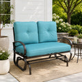 Kozyard outdoor patio glider bench featuring premium thick cushioned seating and a heavy-duty steel frame positioned on a cozy residential porch setting. This elegant two-seater loveseat rocker showcases a sophisticated design that seamlessly integrates into modern backyard patios, open decks, and lush garden landscapes. Designed for ultimate outdoor relaxation, the product highlights plush back support, deep seat comfort, and smooth gliding motion for contemporary home exteriors.