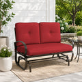 Kozyard outdoor patio glider bench featuring premium thick cushioned seating and a heavy-duty steel frame positioned on a cozy residential porch setting. This elegant two-seater loveseat rocker showcases a sophisticated design that seamlessly integrates into modern backyard patios, open decks, and lush garden landscapes. Designed for ultimate outdoor relaxation, the product highlights plush back support, deep seat comfort, and smooth gliding motion for contemporary home exteriors.