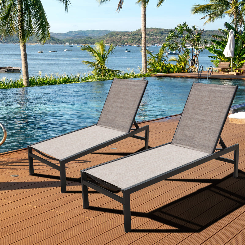 Two beige outdoor lounge chairs with black frames are set on a wooden deck by a swimming pool, with a picturesque view of a body of water, palm trees, and distant hills in the background.Beige Outdoor Lounge Chairs: Relax by the Pool with a Scenic View. beige outdoor lounge chairs, poolside loungers, scenic view, wooden deck furniture, black - framed lounge chairs. 