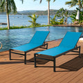 Two blue outdoor lounge chairs with black frames are set on a wooden deck by a swimming pool, with a picturesque view of a body of water, palm trees, and distant hills in the background. blue outdoor lounge chairs, poolside loungers, scenic view, wooden deck furniture, black-framed lounge chairs.
