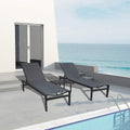 Two gray outdoor lounge chairs with black frames and a matching small side table are positioned on a concrete patio beside a swimming pool, with a stunning view of the sea in the background. The setting includes a modern white building with glass - paneled doors, enhancing the luxurious and relaxing atmosphere. Gray Outdoor Lounge Chairs: Relax by the Pool with a Sea View. gray outdoor lounge chairs, black - framed lounge chairs, poolside furniture, sea - view relaxation, outdoor side table.