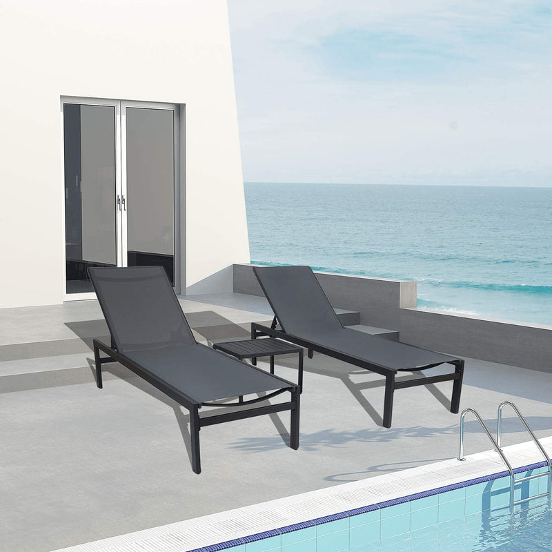 Two gray outdoor lounge chairs with black frames and a matching small side table are positioned on a concrete patio beside a swimming pool, with a stunning view of the sea in the background. The setting includes a modern white building with glass - paneled doors, enhancing the luxurious and relaxing atmosphere. Gray Outdoor Lounge Chairs: Relax by the Pool with a Sea View. gray outdoor lounge chairs, black - framed lounge chairs, poolside furniture, sea - view relaxation, outdoor side table.
