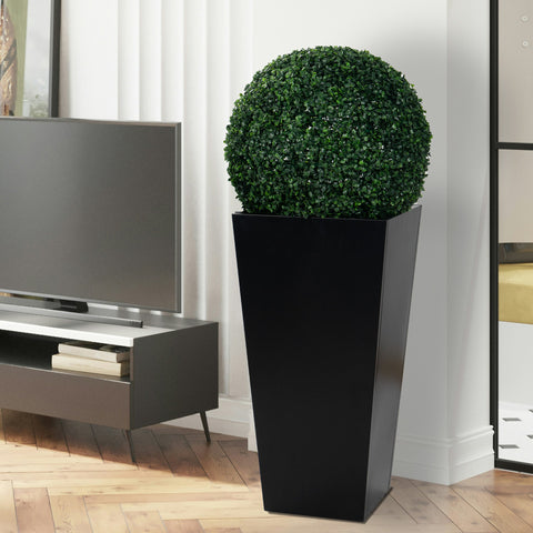 A tall, black metal taper planter indoors, holding a lush, spherical green plant. Its sleek design complements modern interior decor, making it suitable for both indoor and outdoor use to enhance any space with greenery. Tall Taper Black Metal Planter for Indoor and Outdoor Greenery. Tall taper planter, black metal, indoor - outdoor planters, flower plant pot