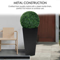 A tall, black metal taper planter with a sleek matte finish, holding a spherical green plant. Crafted from quality metal, it suits both indoor and outdoor settings, enhancing decor with a touch of greenery. Tall Taper Black Metal Planter - Quality Metal Construction. Tall taper planter, black metal, indoor - outdoor planters, metal construction.