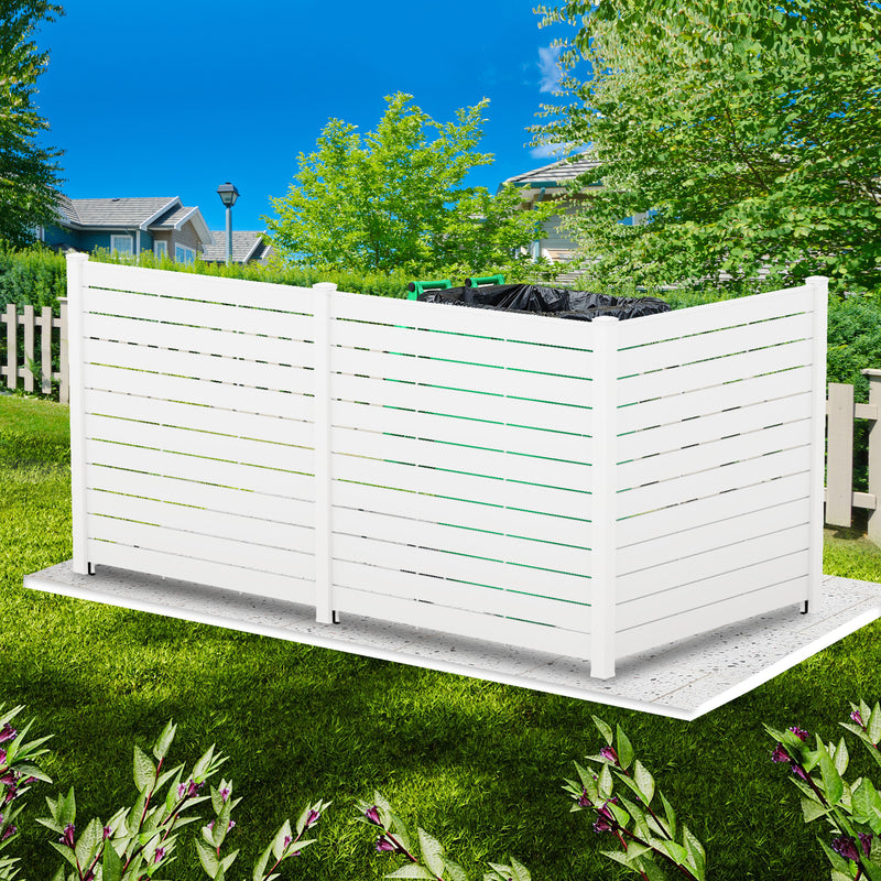 A white outdoor privacy fence with horizontal slats, positioned on a paved base in a grassy yard. The fence conceals trash cans behind it, with a backdrop of greenery, houses, and a clear blue sky.White Outdoor Fence: Ideal for Concealing Yard Items. outdoor fence, white privacy fence, yard concealment, trash can cover, garden fence