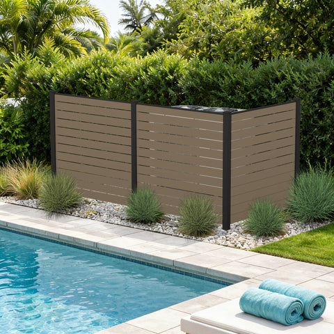 Kozyard 3-panel outdoor privacy screen fence enclosure standing poolside to hide backyard utilities. This premium taupe WPC wood plastic composite privacy fence panel features a heavy-duty black aluminum frame, beautifully concealing dual air conditioner condenser units or pool pumps. Freestanding decorative yard screening structure perfectly blends with landscaping rocks and green gardens while enhancing deck or patio aesthetics.