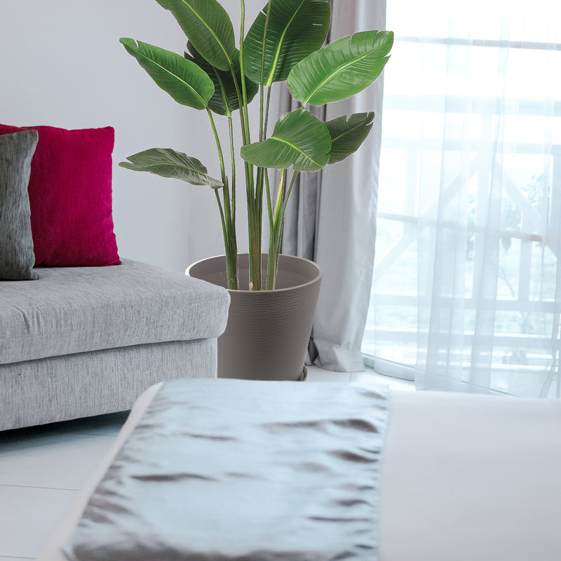 In a cozy living room setting, a sleek brown plastic plant pot holds a lush, green tropical plant. The pot is placed beside a light - colored sofa adorned with a red and a gray cushion, near a window with sheer curtains, creating a warm and inviting indoor atmosphere.Brown Plastic Plant Pot: Elevate Your Indoor Living Space. Brown plastic plant pot, indoor planter, living room decor, tropical plant pot, home decor planter