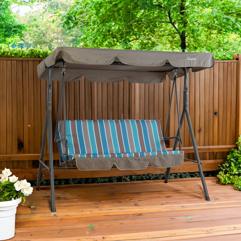 A Kozyard outdoor swing chair placed on a wooden deck, set against a backdrop of a wooden fence and lush green foliage. The swing features a sturdy metal frame, a canopy in a muted gray - brown color, and a seat cushion with vibrant blue and gray stripes. Kozyard Outdoor Swing Chair: Relax in Style on Your Deck. Kozyard swing chair, outdoor patio swing, striped - cushion swing, swing with canopy, wooden deck swing