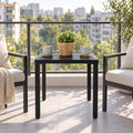 Kozyard black outdoor side table placed between patio chairs on a modern balcony, featuring a compact square slatted metal top and sturdy four-leg frame. This space-saving patio end table is ideal for coffee, drinks, plants and outdoor décor, making it a practical choice for apartments, balconies, decks, porches and small outdoor conversation areas.