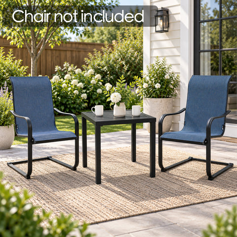 Kozyard compact black outdoor side table shown between two blue patio chairs on a covered porch, featuring a modern square slatted tabletop and sturdy metal legs. Perfect as a patio end table for drinks, plants and décor in gardens, decks, balconies and small outdoor spaces. Chairs are not included; image demonstrates table scale and versatile placement.