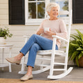 Senior woman relaxing with coffee on Kozyard white solid wood porch rocker, ergonomic garden rocking chair for lawn and deck.