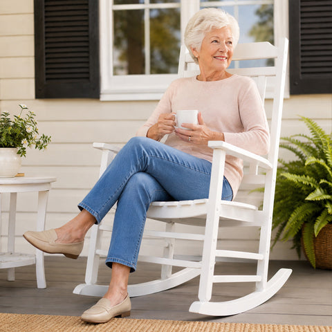 Senior woman relaxing with coffee on Kozyard white solid wood porch rocker, ergonomic garden rocking chair for lawn and deck.