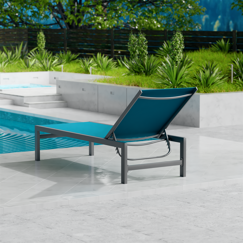 A blue outdoor lounge chair with a dark frame is set on a sleek, light-colored tiled area beside a swimming pool. The background features lush greenery and a wooden fence, creating a serene outdoor relaxation spot. blue outdoor lounge chair, poolside lounge chair, outdoor relaxation furniture, dark-framed lounge chair.
