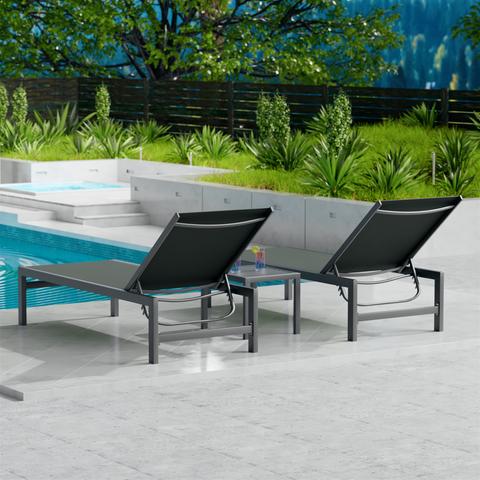 Two gray outdoor lounge chairs with dark metal frames are placed beside a swimming pool. The surrounding area features lush greenery and a wooden fence, creating a serene and inviting outdoor relaxation space. gray outdoor lounge chairs, poolside loungers, outdoor relaxation furniture, dark-framed lounge chairs.