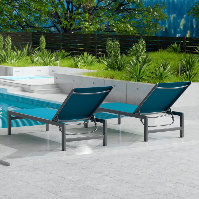 Two blue outdoor lounge chairs with dark metal frames are placed beside a swimming pool. The surrounding area features lush greenery and a wooden fence, creating a serene and inviting outdoor relaxation space. blue outdoor lounge chairs, poolside loungers, outdoor relaxation furniture, dark-framed lounge chairs.