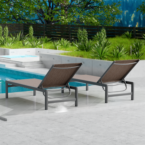 Two beige outdoor lounge chairs with dark metal frames are placed beside a swimming pool. The surrounding area features lush greenery and a wooden fence, creating a serene and inviting outdoor relaxation space. Beige Outdoor Lounge Chairs: Relax by the Pool in Style. beige outdoor lounge chairs, poolside loungers, outdoor relaxation furniture, dark - framed lounge chairs.