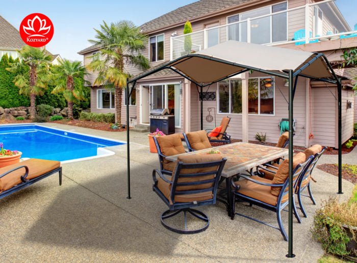 A KOZYARD Sun Shade Gazebo is set up beside a backyard swimming pool, providing shade over an outdoor dining area with cushioned chairs and a table. The scene includes a two - story house in the background, enhancing the inviting outdoor living space. KOZYARD Sun Shade Gazebo for Backyard Relaxation.KOZYARD sun shade gazebo, backyard, swimming pool, outdoor dining, shade structure.