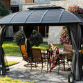 Outdoor Patio Gazebo with Furniture Setup
A black outdoor patio gazebo with a slatted roof and draped curtains, featuring a dining table and chairs set, surrounded by greenery and decorative elements like lanterns. Keywords: outdoor patio gazebo, outdoor dining setup, decorative elements